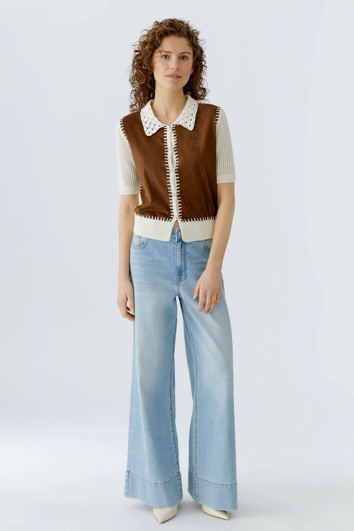 Modèle portant une blouse manches courtes avec col ajouré et détails artisanaux, associée à un jean ample pour un look raffiné.