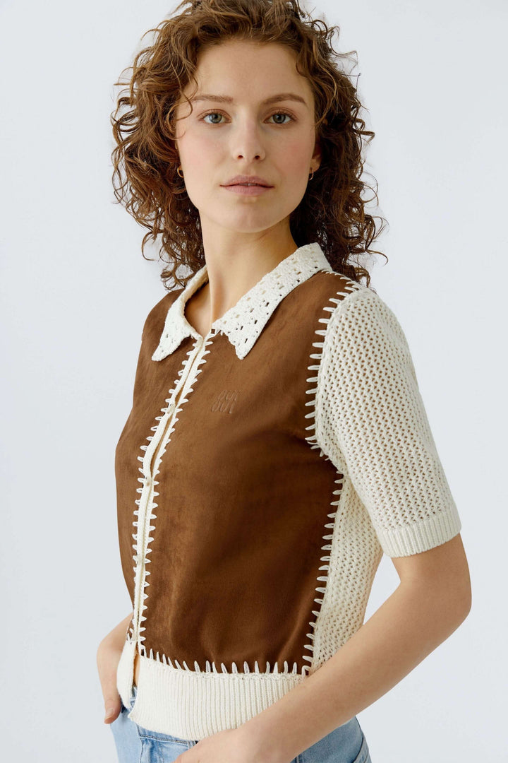 Blouse manches courtes avec col ajouré et détails contrastants artisanaux, coupe droite mettant en valeur la silhouette féminine.