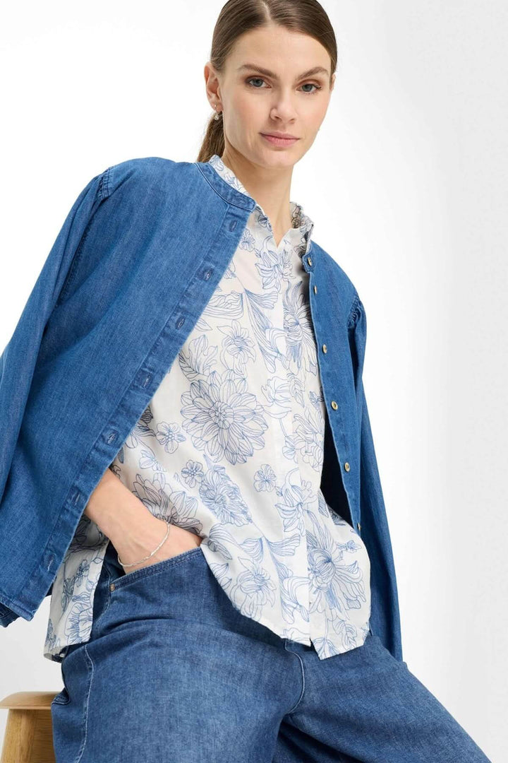 Blouse à motif floral VICKI portée avec élégance, mettant en valeur son motif délicat et sa fluidité sous une veste en denim.