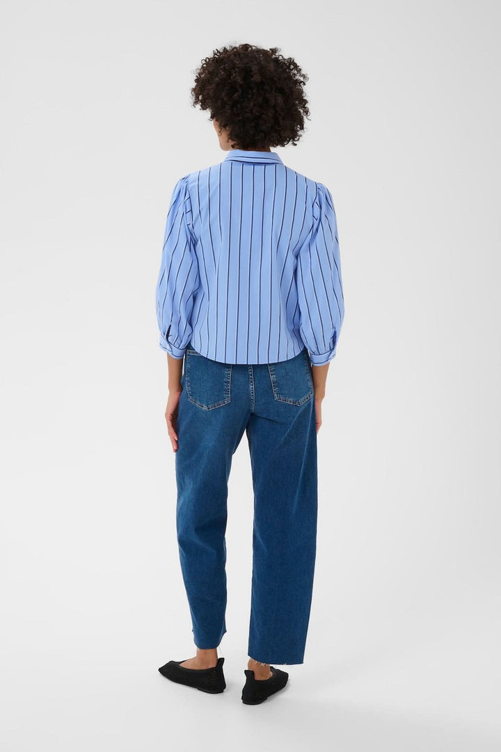 Vue arrière de la blouse rayée Anais en bleu avec manches bouffantes, portée sur un jean pour un style décontracté mais raffiné.