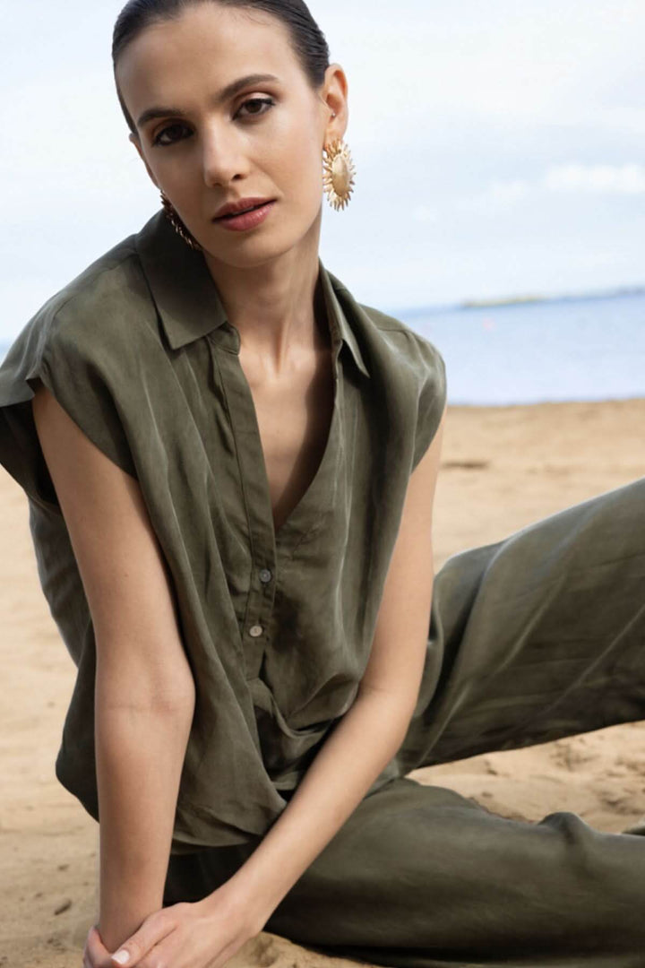Femme portant une blouse sans manches à col chemise en plein air, style moderne et élégant.
