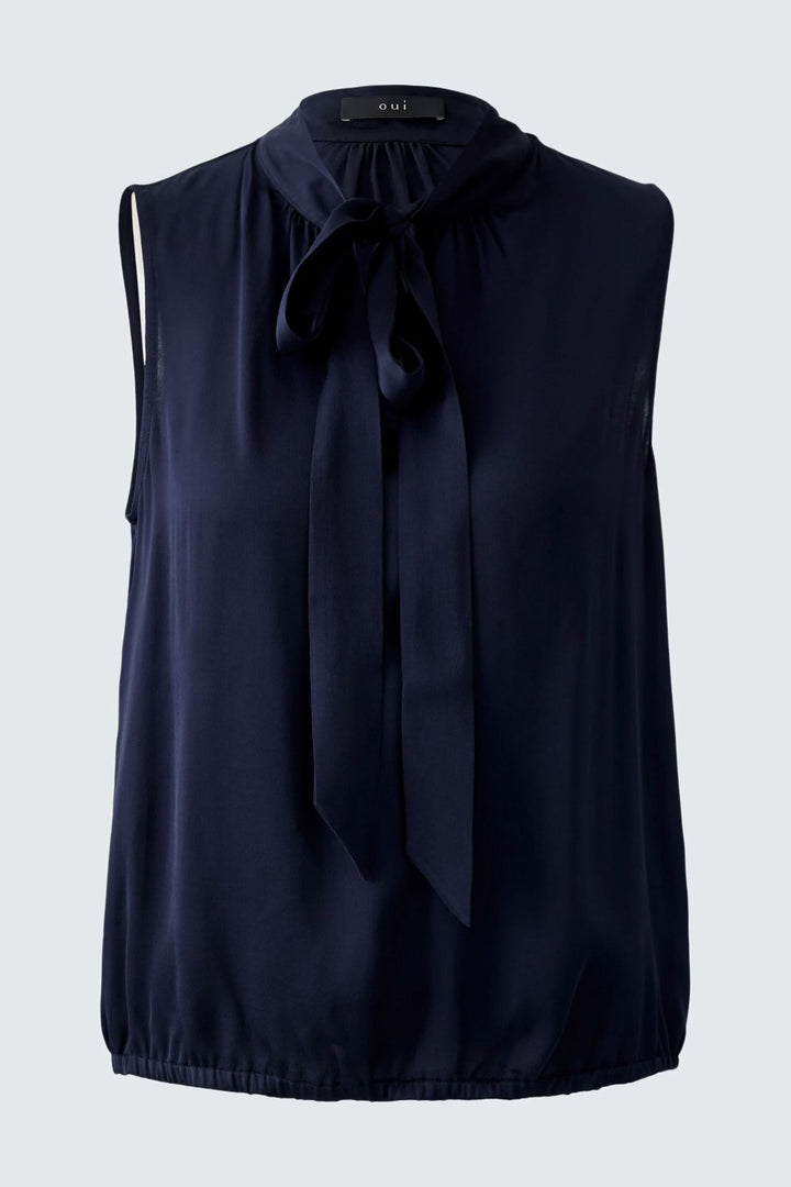 Blouse évasée en satin, col légèrement montant, manches sans, couleur navy, silhouette décontractée avec ceinture élastiquée.