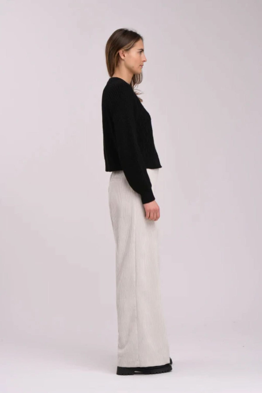 Cardigan noir à motif texturé, porté avec un pantalon ample pour un look élégant et chic.