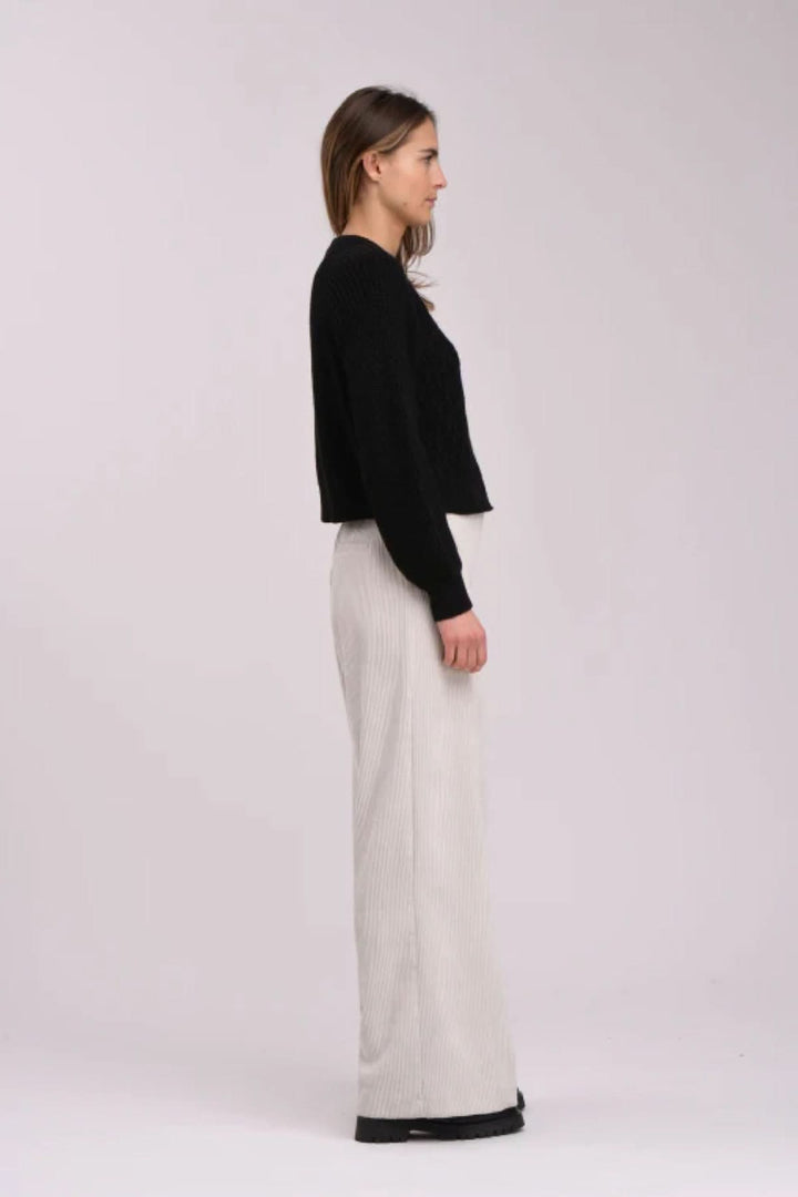 Cardigan noir à motif texturé, porté avec un pantalon ample pour un look élégant et chic.