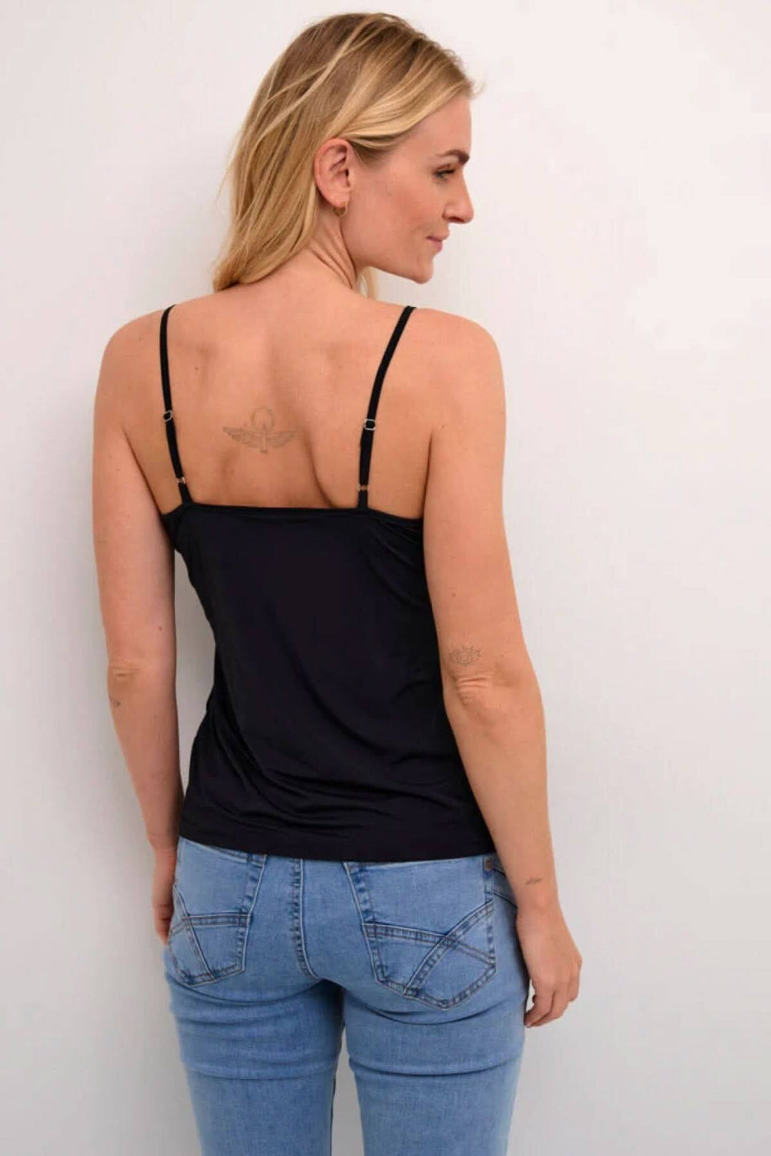 Camisole noire légère avec bretelles ajustables, coupée pour un ajustement flatteur, portée avec un jean.