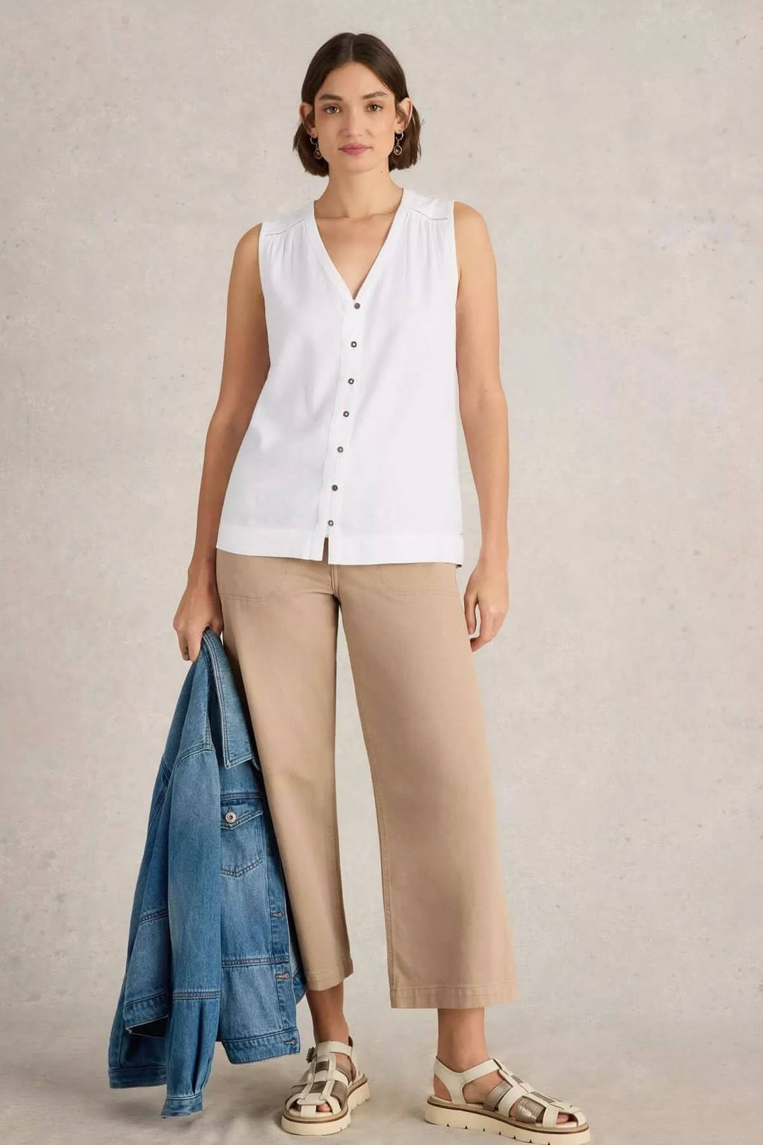 Camisole Delilah sans manches en V, portée avec pantalon beige et veste en jean, style estival et élégant.