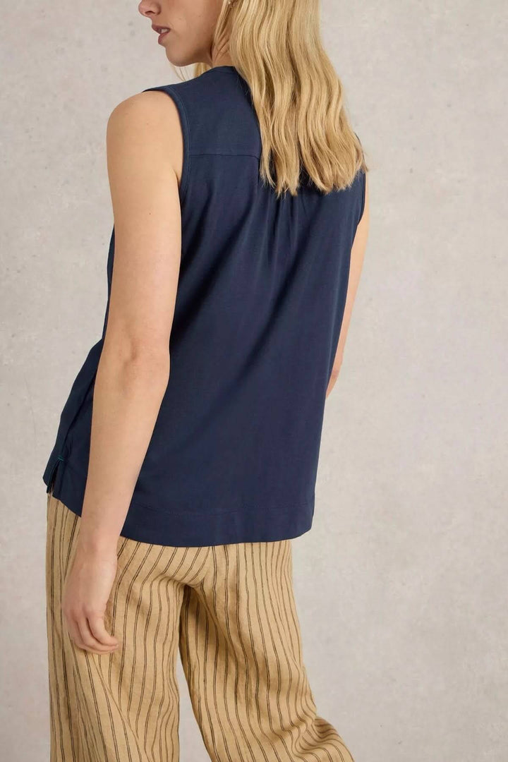 Camisole Delilah sans manches, col en V, coupes fluide, portée avec pantalon beige, style estival et élégant.