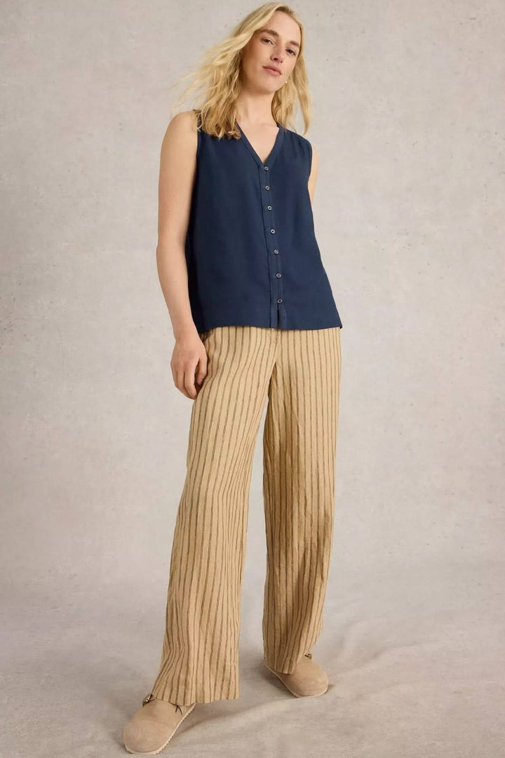 Camisole Delilah sans manches, encolure en V, portée avec un pantalon beige à rayures pour un look estival élégant.