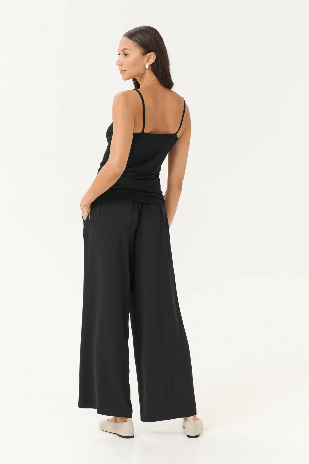 Femme portant une camisole Frida à bretelles réglables avec un pantalon noir fluide, vue de dos.