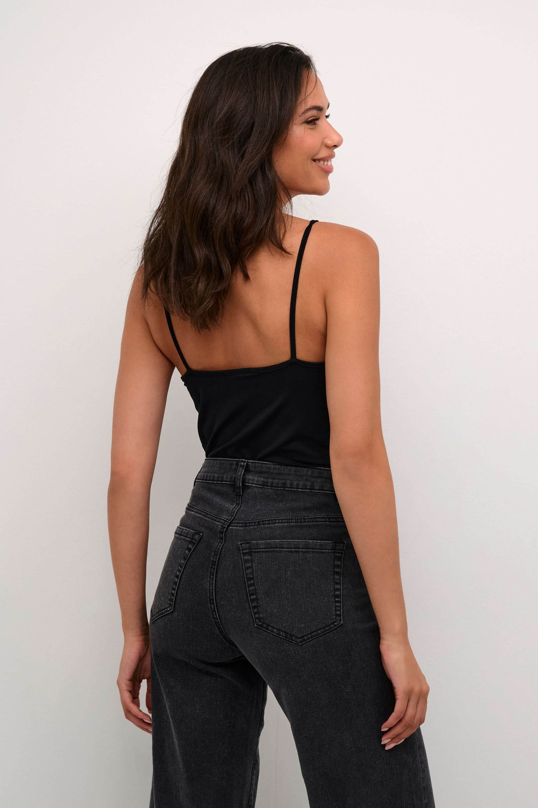 Camisole Frida à bretelles réglables, portée avec un pantalon noir, style décontracté et moderne.