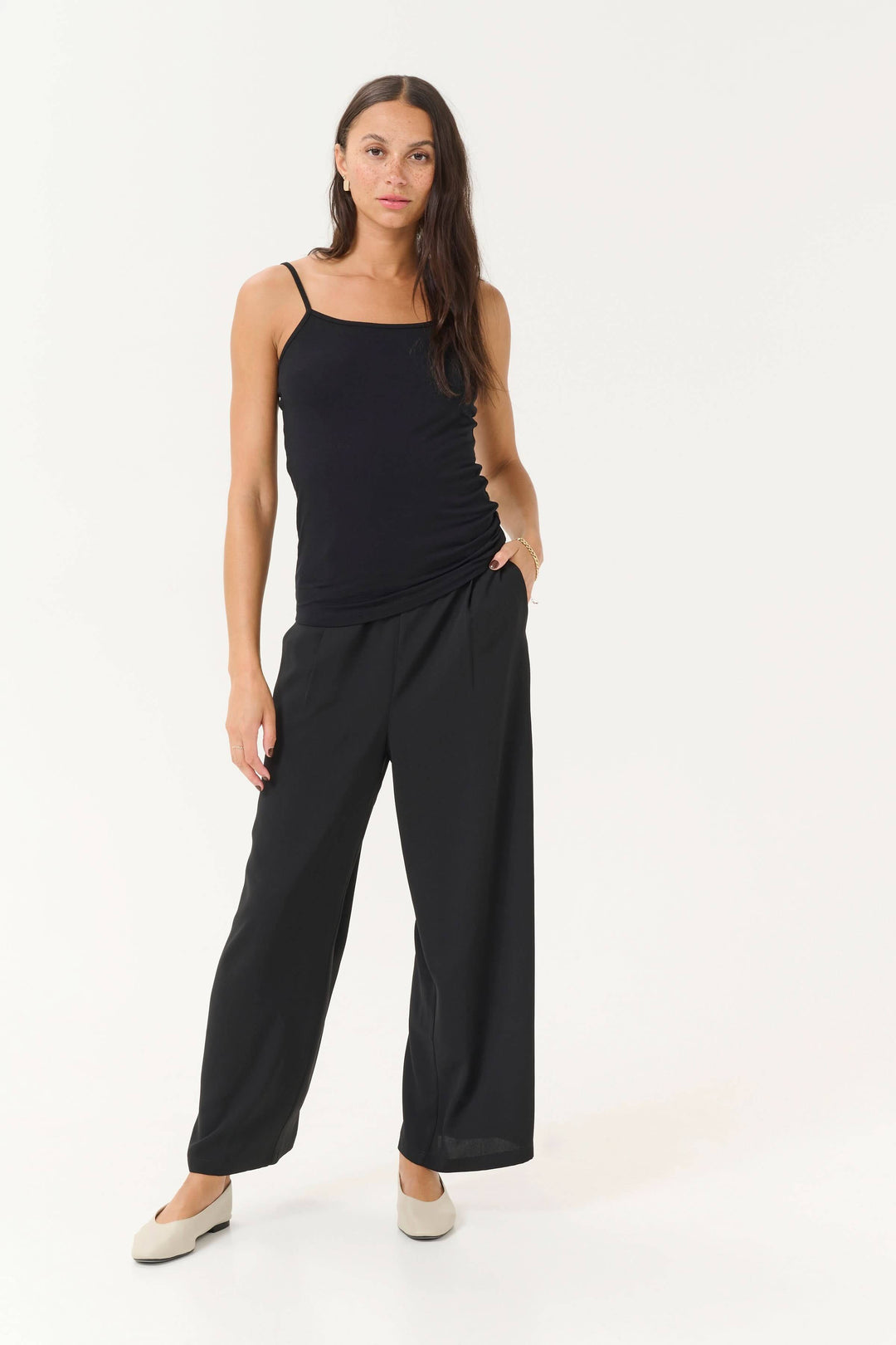 Camisole Frida noire avec bretelles réglables, associée à un pantalon large pour un look élégant et décontracté.