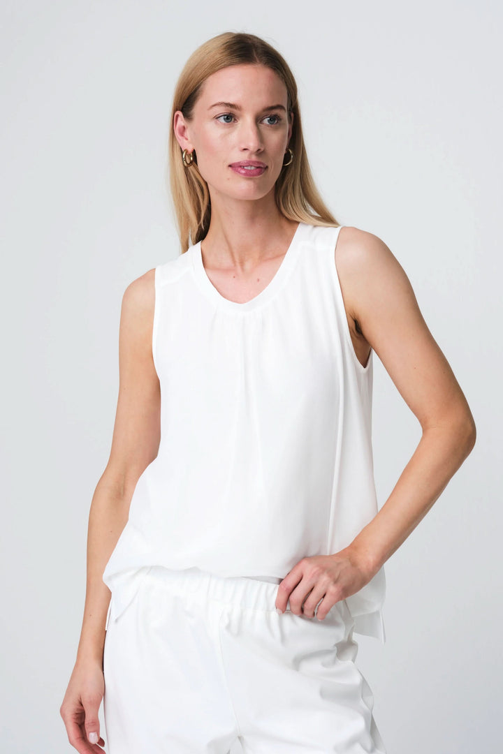 Femme portant Camisole Gini fluide sans manches avec encolure dégagée, coupe droite et ourlet arrondi, style élégant.