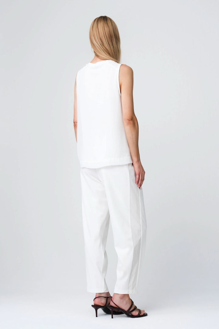 Dos de mannequin portant la Camisole Gini fluide sans manches, coupe droite en tissu blanc, assortie à un pantalon élégant et fluide.