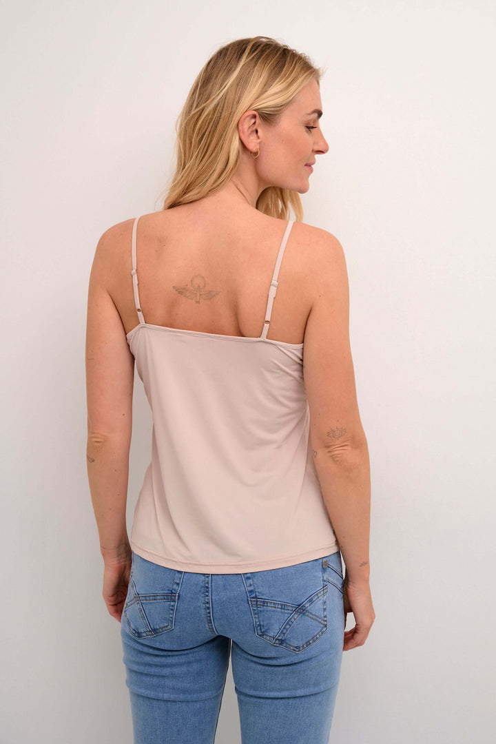Femme portant la Camisole Lissandra beige avec fines bretelles et coupe ajustée, vue de dos.