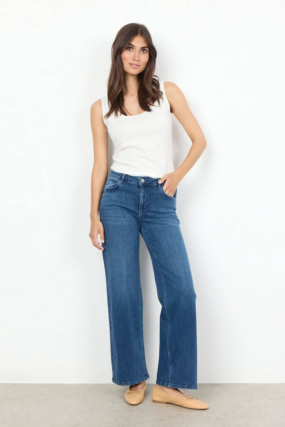 Femme portant une camisole basique blanche et un jean large, affichant un look décontracté et élégant.