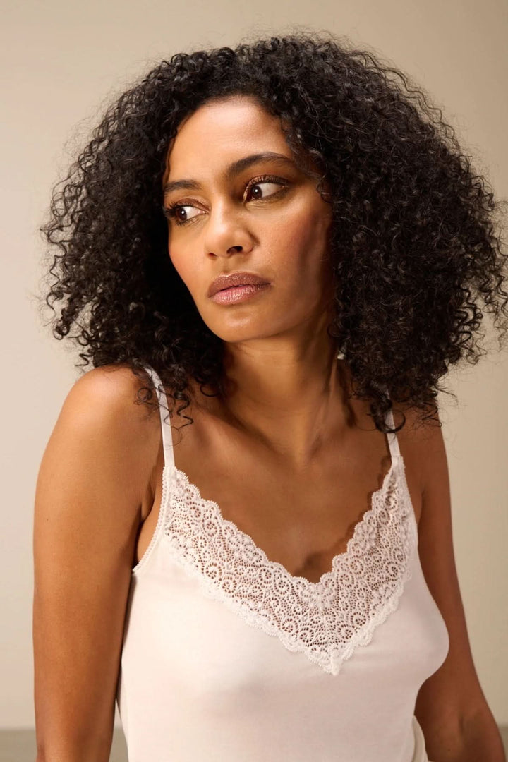 Femme portant une camisole à bretelles avec dentelle, encolure en V raffinée, silhouette épurée et confortable.