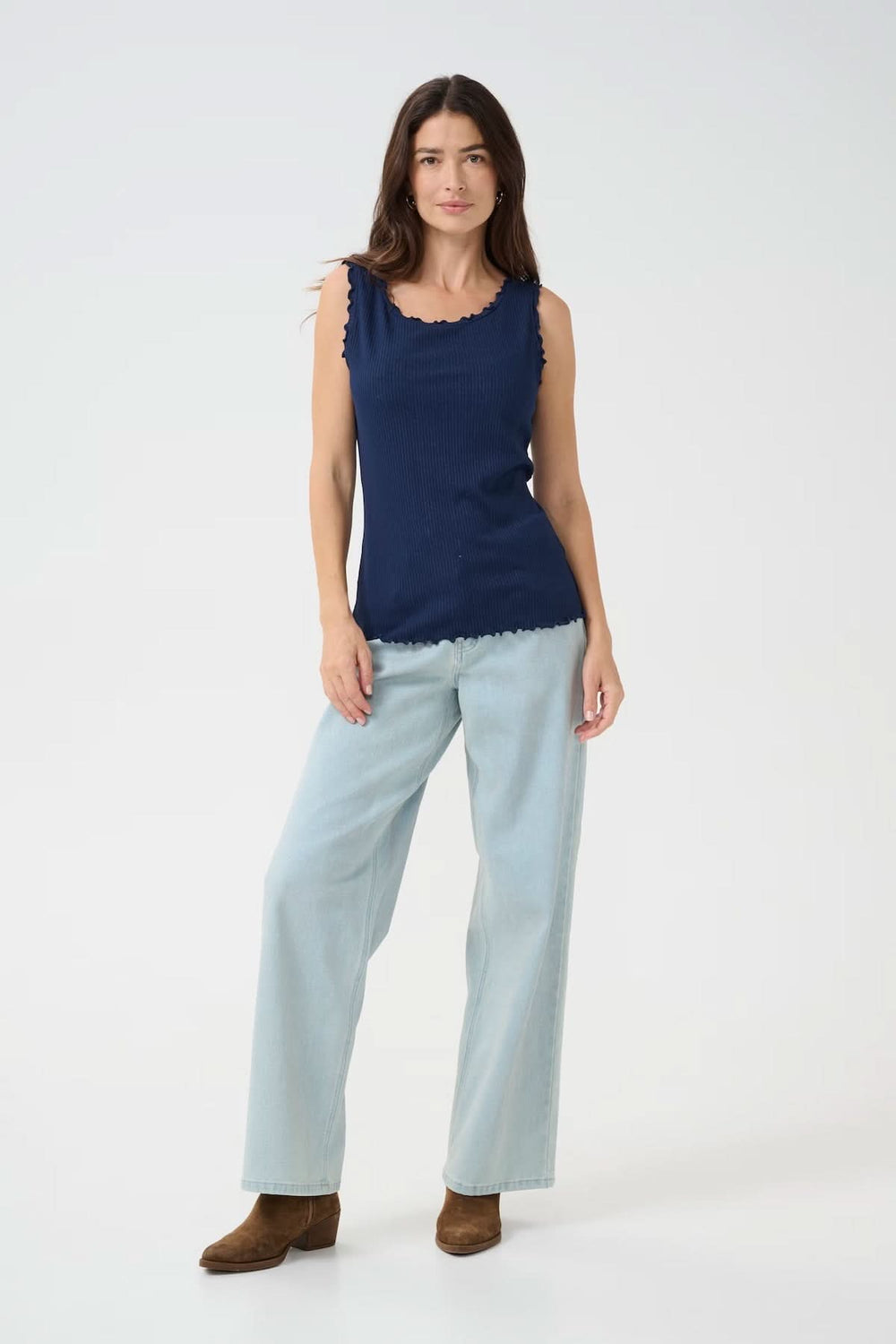 Camisole sans manches navy avec détails froncés, portée avec un pantalon clair pour un look estival décontracté.
