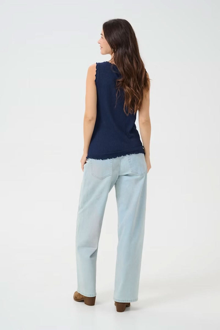 Femme portant une camisole à col froncé, vue de dos, associée à un pantalon clair pour un look estival décontracté.