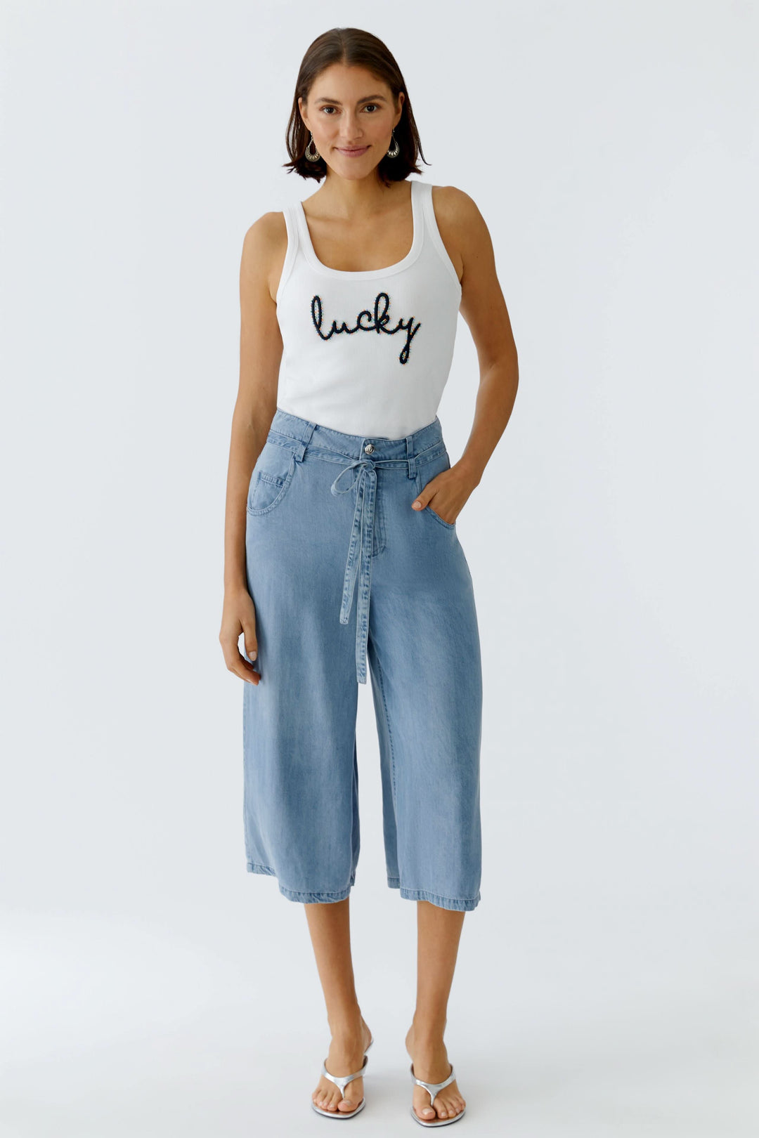 Camisole côtelée avec inscription brodée portée avec un jean ample, confort et style décontracté à la mode.