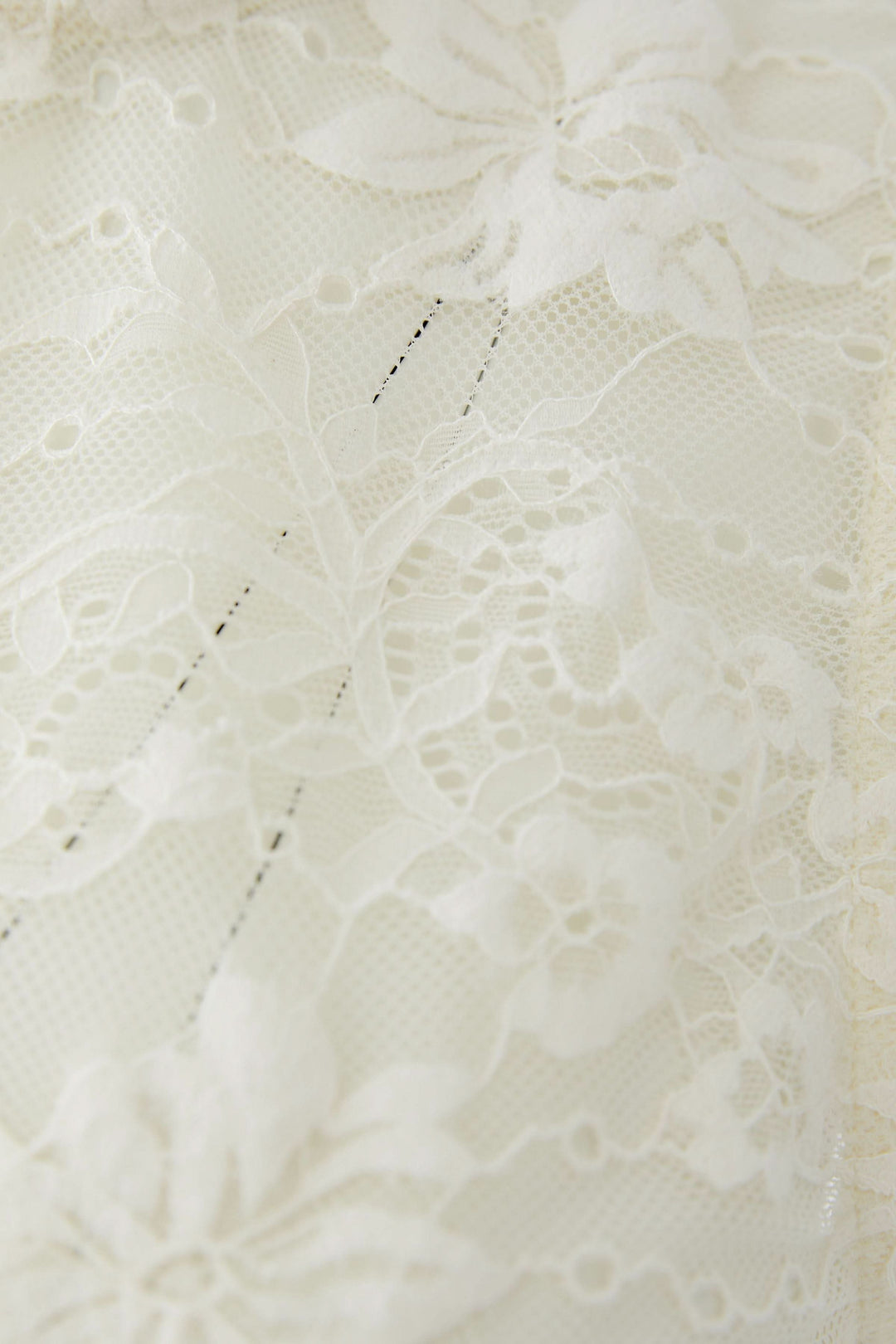 Détail de dentelle florale de la camisole en dentelle florale, affichant un motif délicat et raffiné.