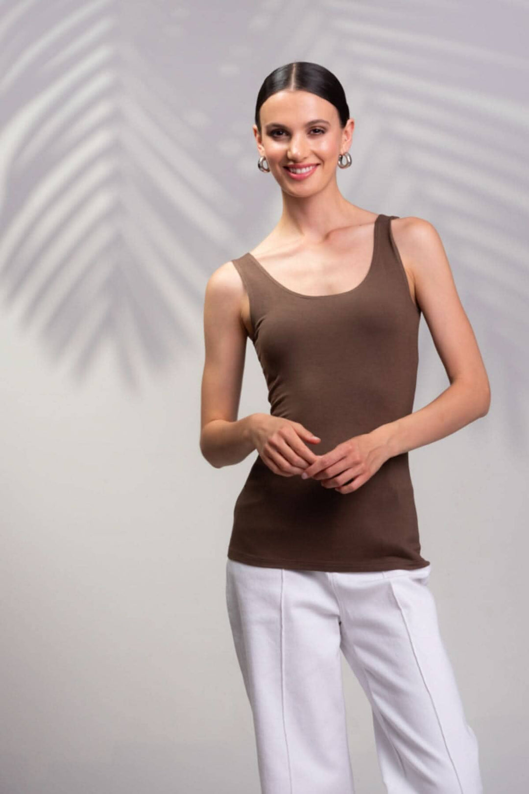 Camisole encolure carrée marron avec bretelles larges, portée par un modèle, fond flou de feuilles.