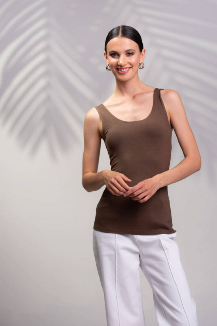 Camisole encolure carrée marron avec bretelles larges, portée par un modèle, fond flou de feuilles.