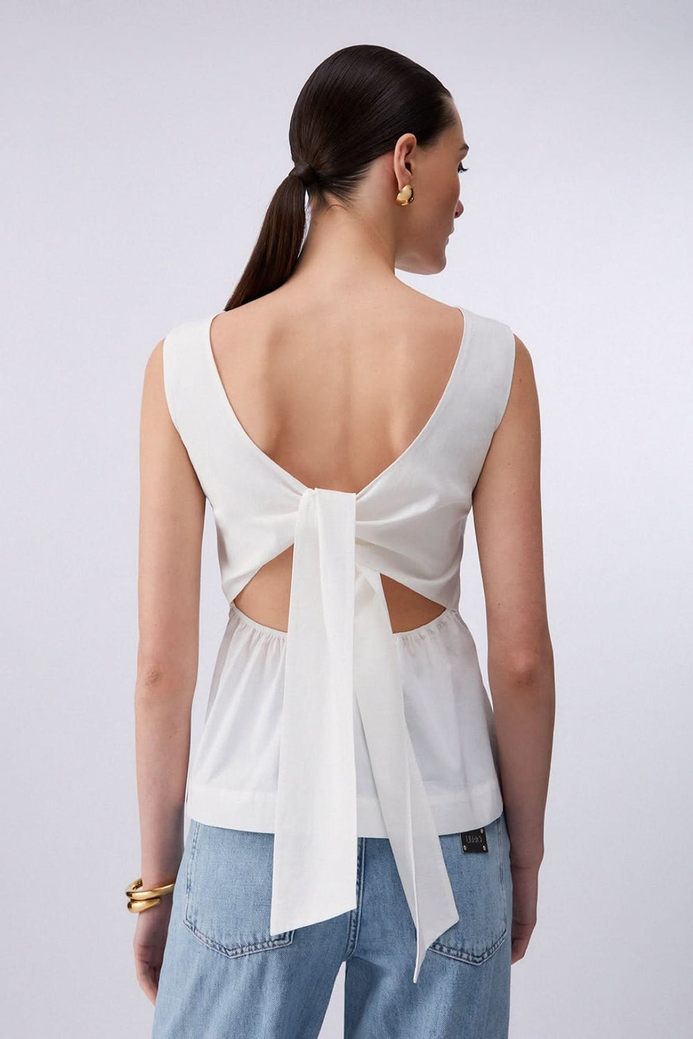 Camisole fluide avec dos ouvert et nœud, détail élégant avec encolure bateau, parfait pour superposer sous une veste ou porter l'été.