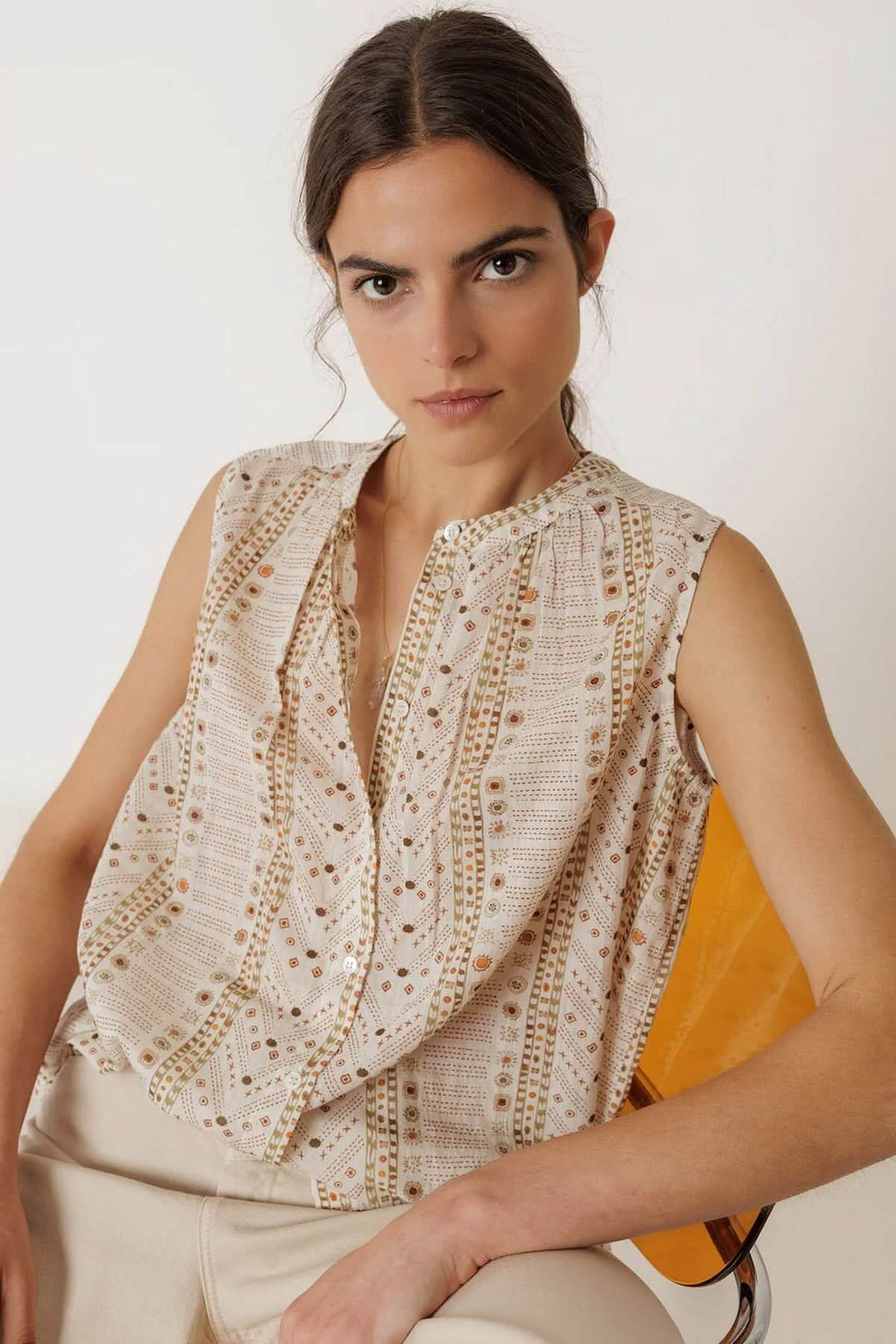 Femme portant une camisole fluide imprimée sans manches avec encolure ronde, tombé élégant et légèrement ample, parfait pour l'été.