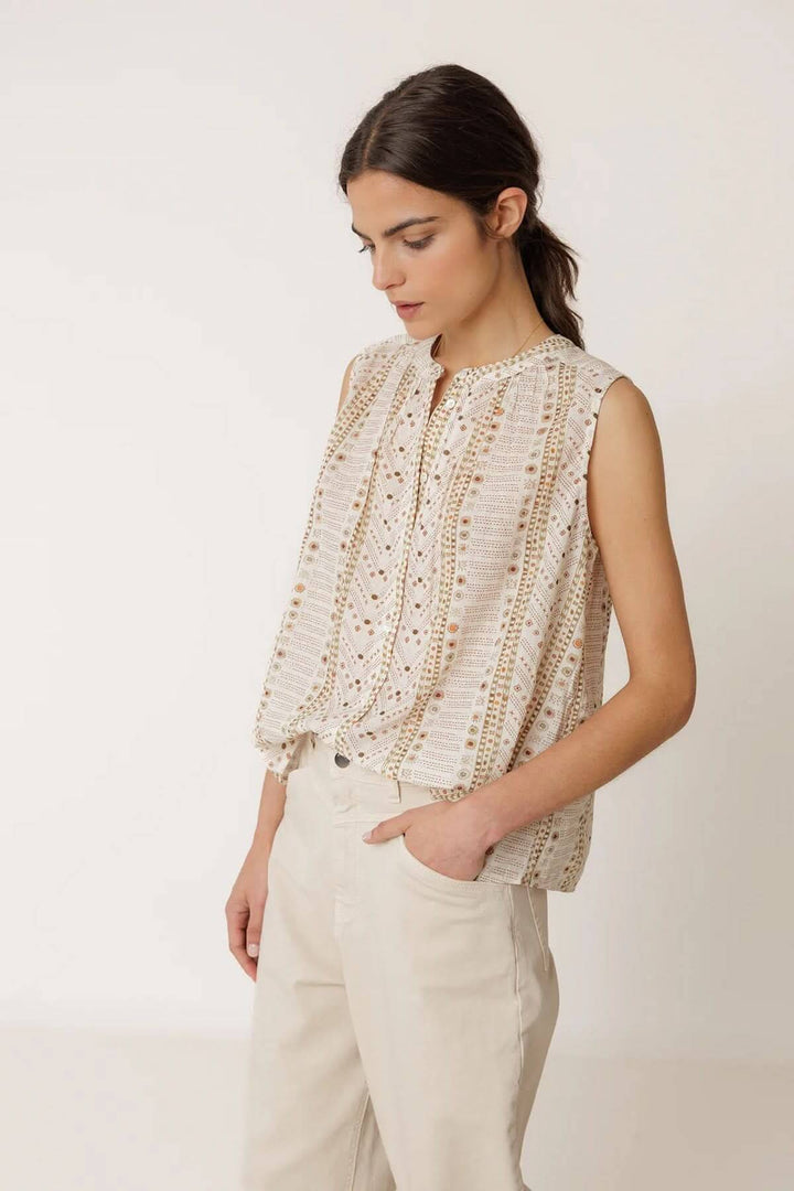 Femme portant une camisole fluide imprimée sans manches avec imprimé délicat, idéale pour un look estival ou décontracté.