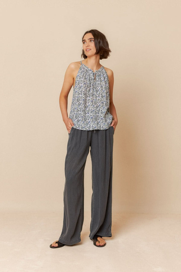 Modèle portant une camisole imprimée fleuri avec bretelles ajustables et pantalon fluide, parfaite pour l'été.
