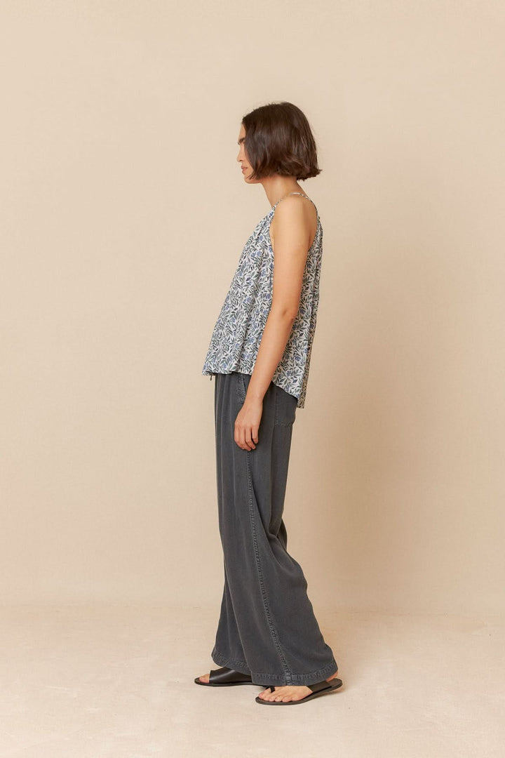 Camisole imprimée fleuri sans manches, encolure en V, portée avec un pantalon ample, look d'été élégant.