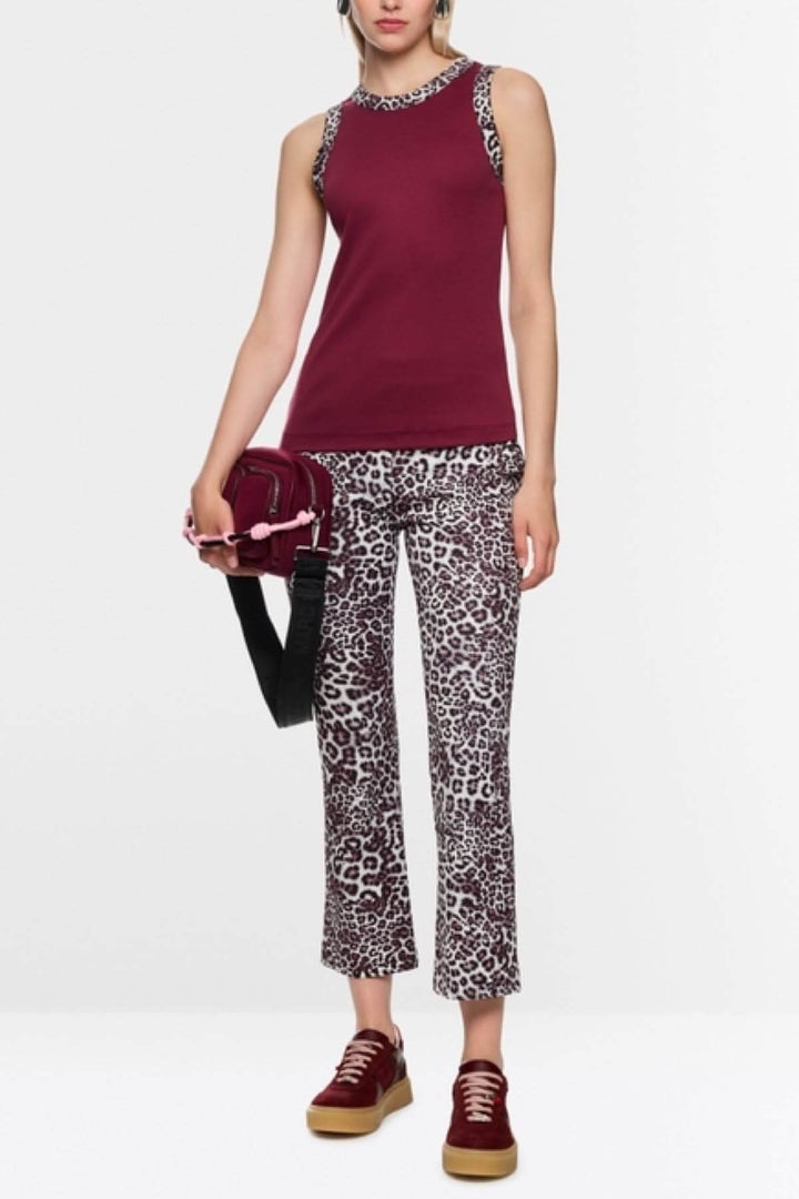 Femme portant une camisole à imprimé léopard avec bordures léopard, tenue moderne et élégante.