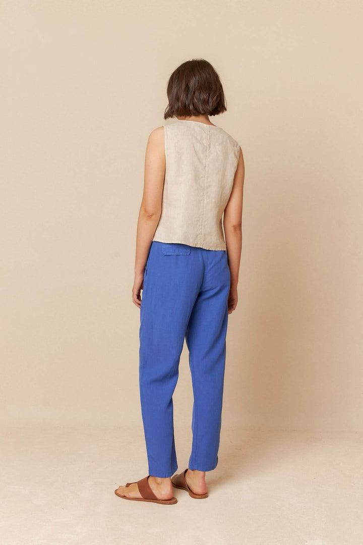 Camisole sans manches beige portée avec un pantalon bleu, vue de dos, style décontracté.
