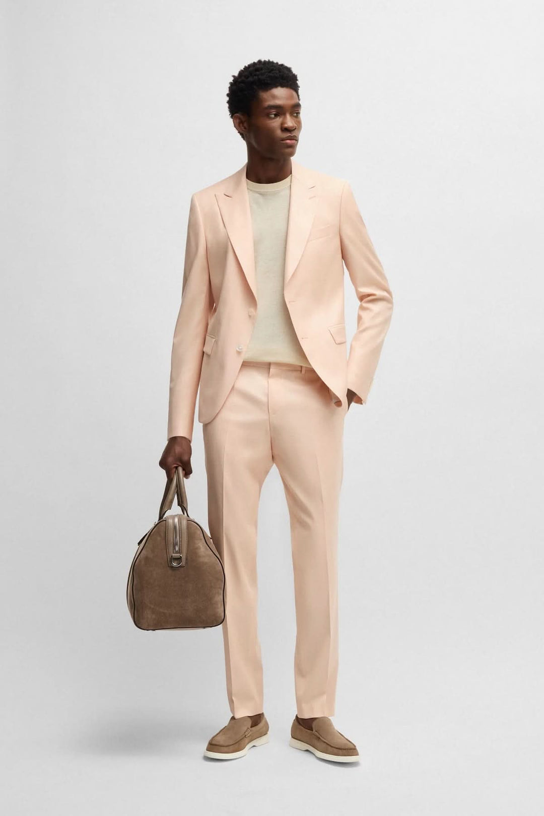 Homme en costume beige clair avec sac, look élégant pour une occasion formelle, automne-hiver.