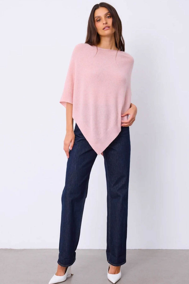 Cape en maille rose portée par une femme, offrant une silhouette fluide et élégante, parfaite pour un look décontracté et raffiné.