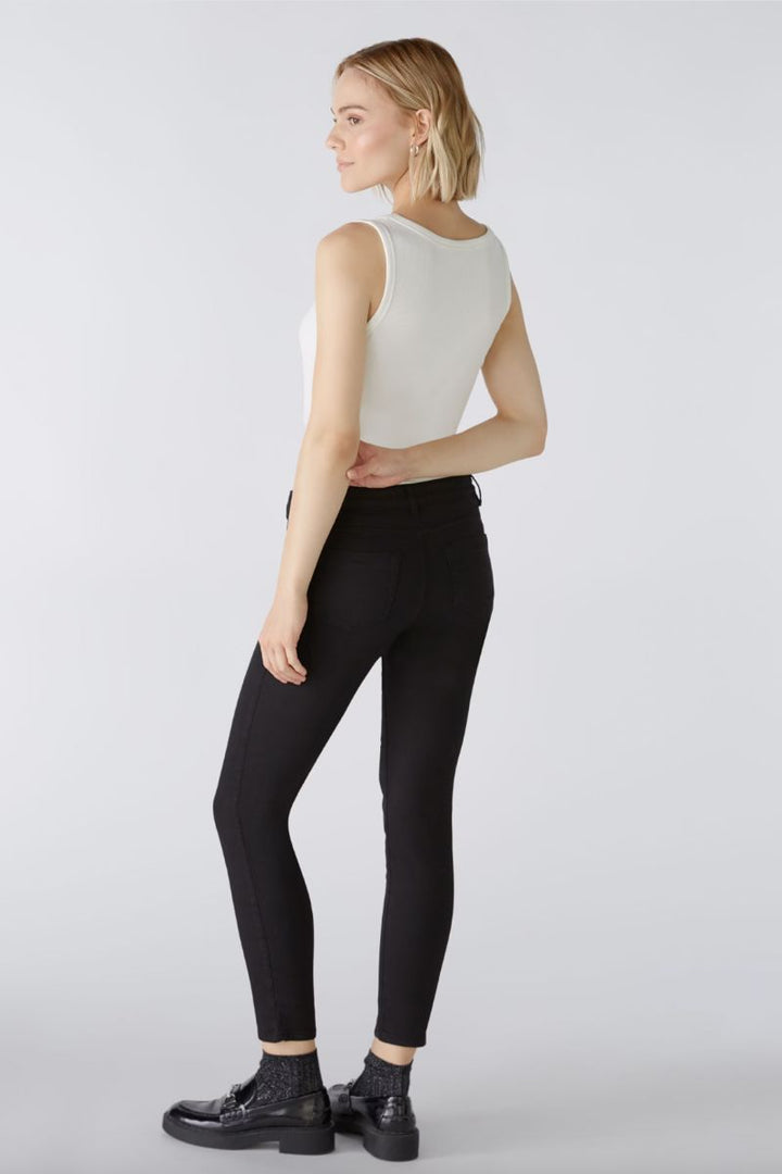 Femme portant un pantalon ajusté noir avec un débardeur blanc, vue arrière.