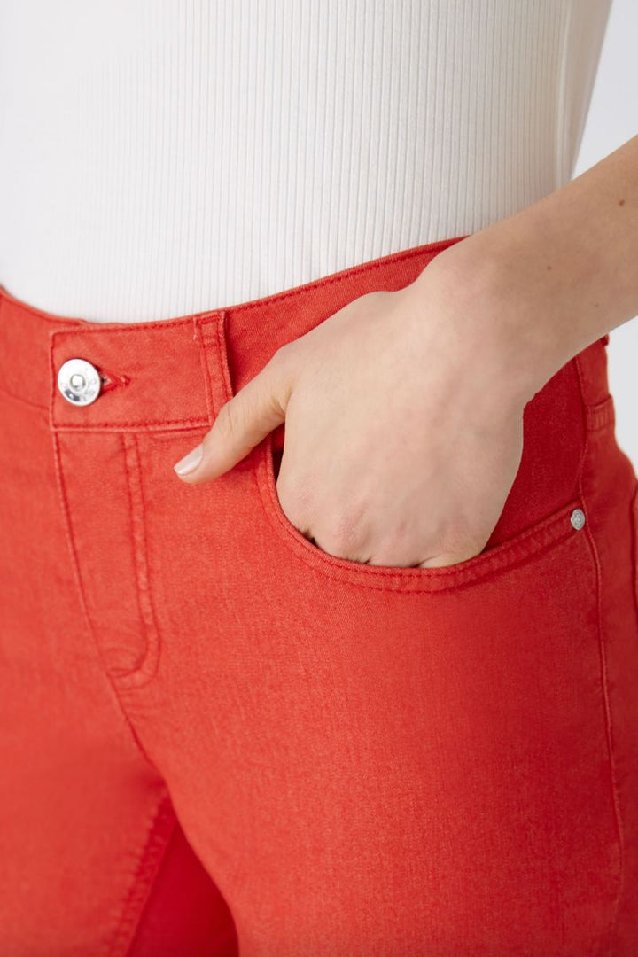 Pantalon ajusté rouge avec une coupe régulière, mettant en avant la poche et la fermeture éclair.