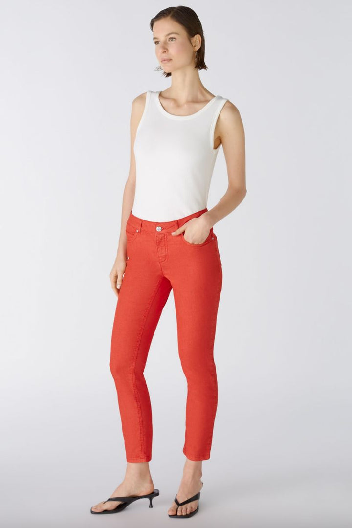 Pantalon ajusté rouge, taille régulière, longueur cheville, avec t-shirt blanc et sandales noires.