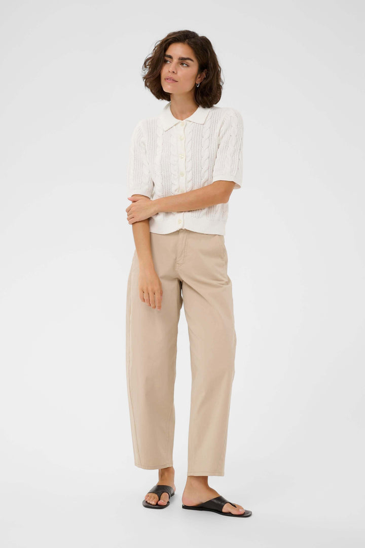 Femme portant un Cardigan Blair en maille torsadée blanche avec col polo et manches courtes, style élégant et soigné.