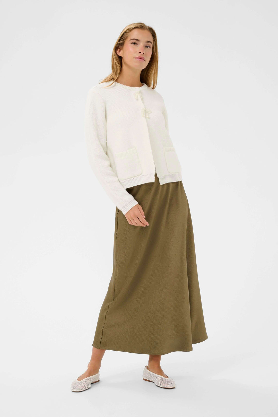 Modèle portant le Cardigan Bowie blanc, style délicat et intemporel, coupe droite avec encolure arrondie et détails féminins à l'avant.