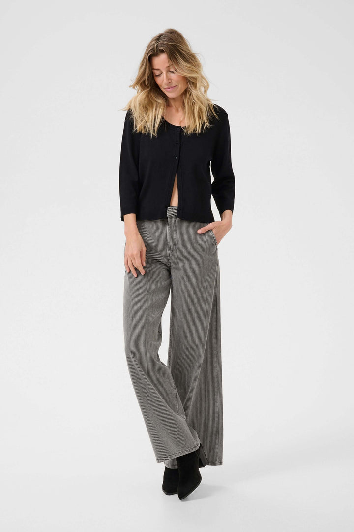 Femme portant un cardigan minimaliste à manches trois-quarts et un pantalon large, style décontracté et élégant.