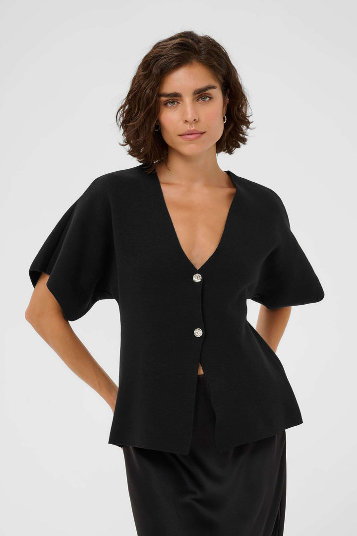 Femme portant Cardigan Jessica noir avec design moderne, coupe légèrement évasée et encolure en V, idéal pour un look élégant.