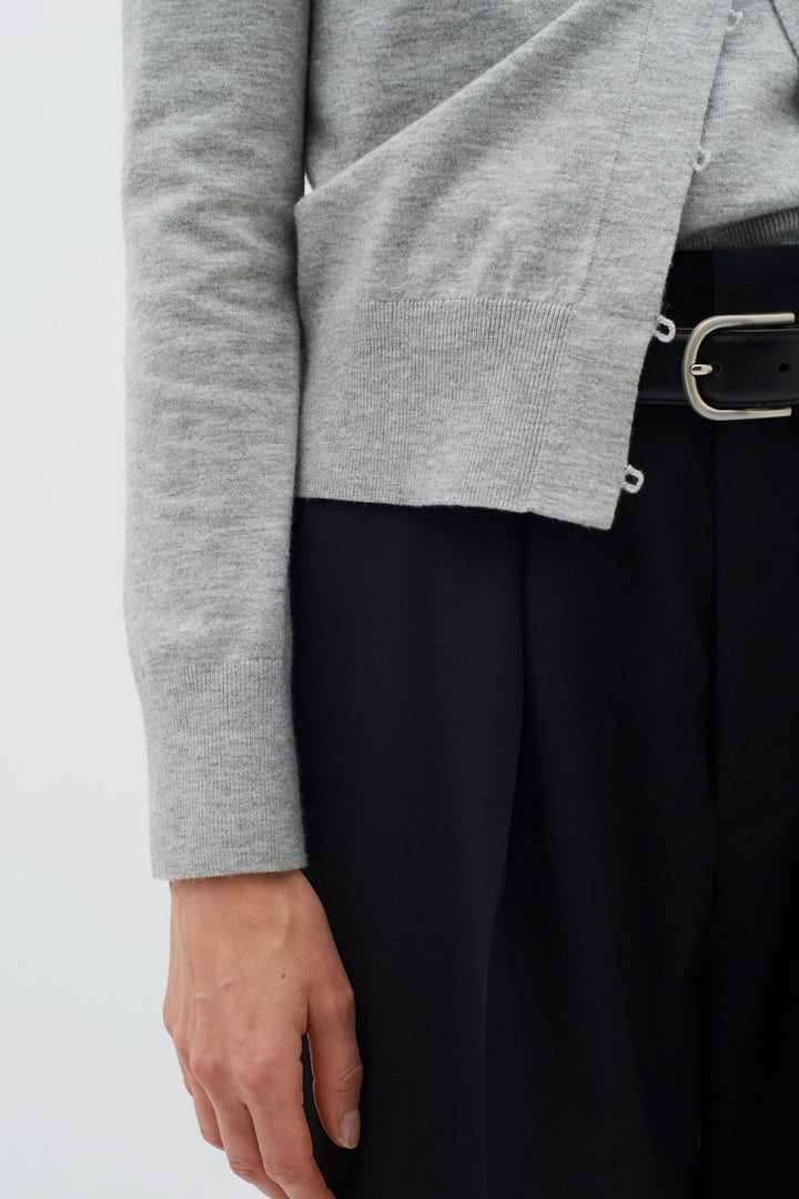 Détail d'un cardigan gris chiné, léger et polyvalent, porté avec un pantalon noir, mettant en valeur une silhouette élégante.