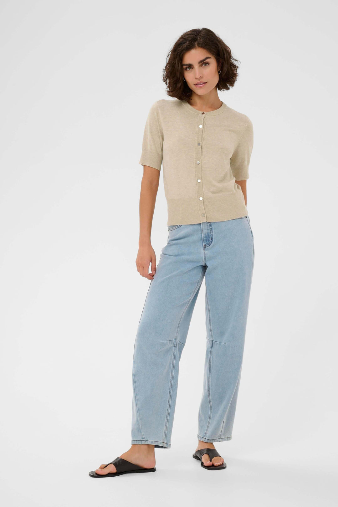 Femme portant le Cardigan Lizza en couleur beige, manches courtes, coupe ajustée, style élégant et décontracté.