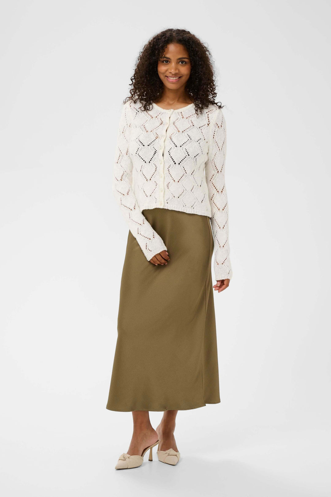 Femme portant le Cardigan Lorinia en maille ajourée, manches longues et encolure ronde, avec une jupe kaki élégante.