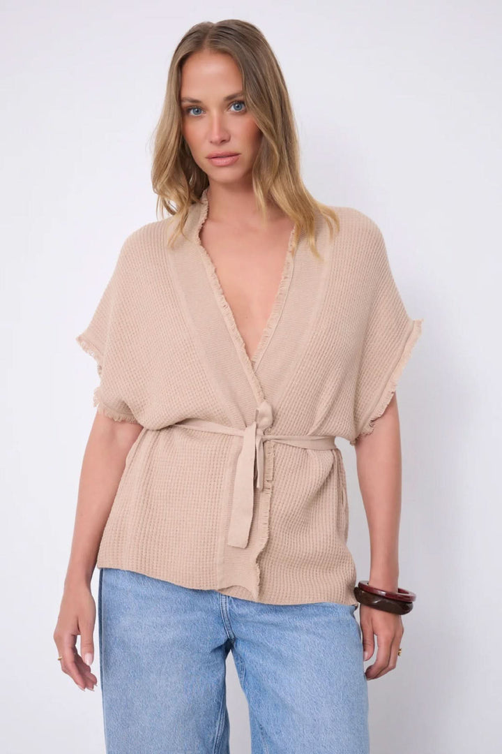 Modèle portant le Cardigan Sonya texturé ceinturé manches courtes, style ample avec ceinture à nouer et col en V.