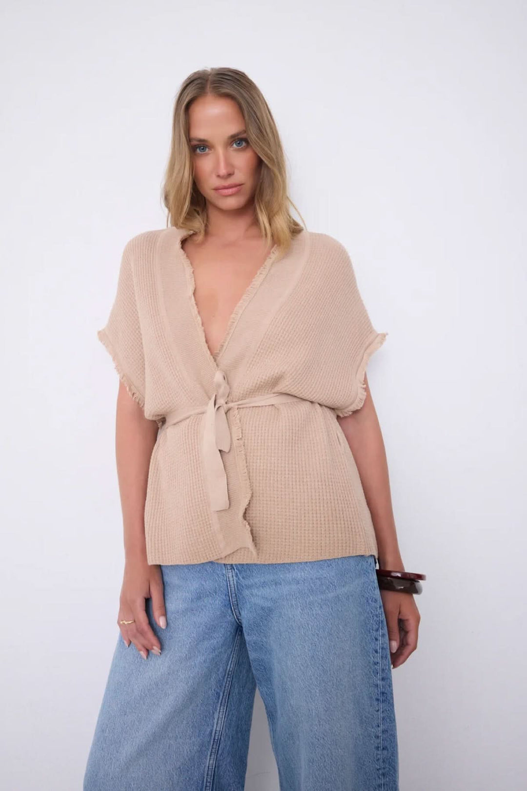 Femme portant le Cardigan Sonya texturé ceinturé manches courtes, style décontracté avec ceinture nouée et col en V profond.