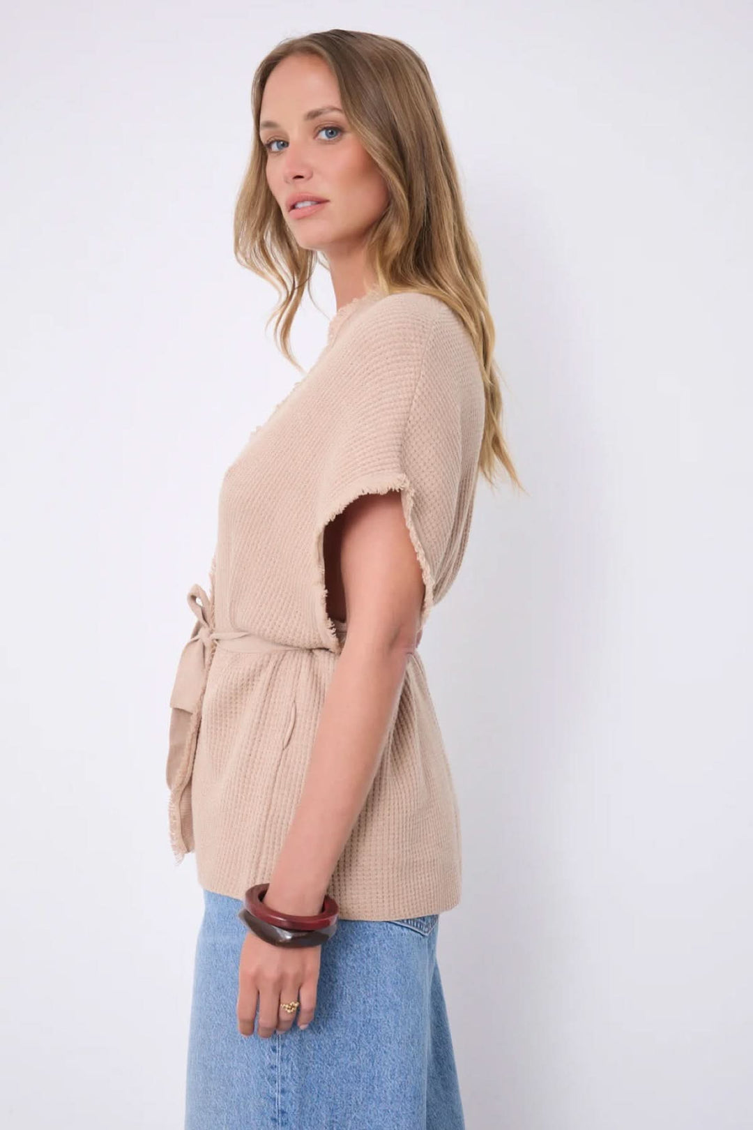 Cardigan Sonya texturé ceinturé manches courtes en tissu gaufré avec ceinture à nouer, vue latérale, femme portant bracelet et jupe en jean.