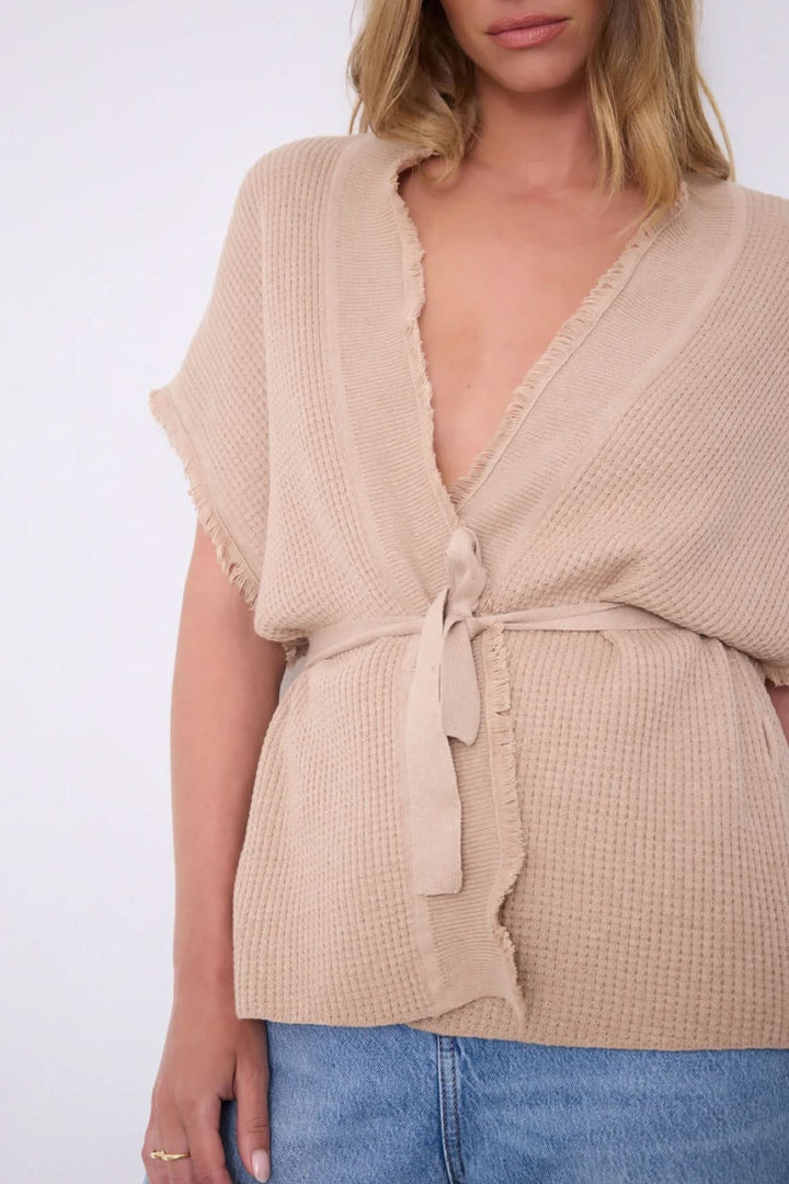 Femme portant le Cardigan Sonya texturé ceinturé manches courtes en beige avec texture gaufrée.