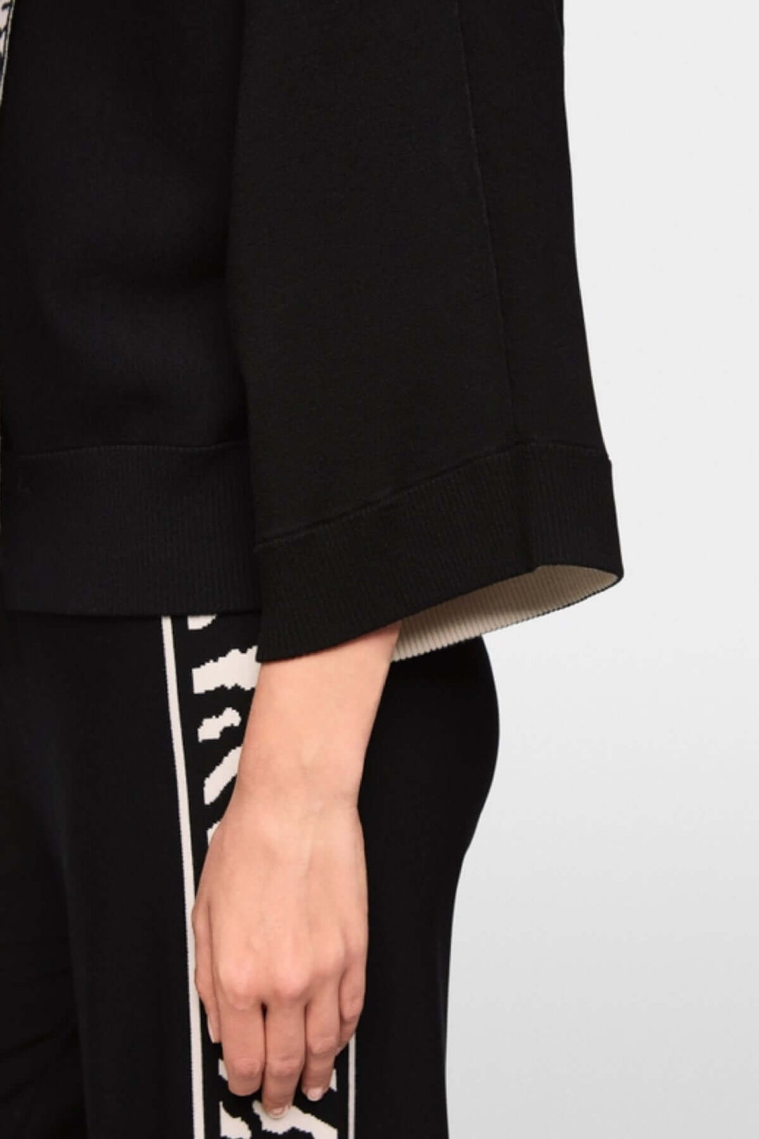 Cardigan avec fermeture éclair, manches 3/4 larges, tissu doux, motifs animaliers contrastés sur le côté, détail de mode élégant.